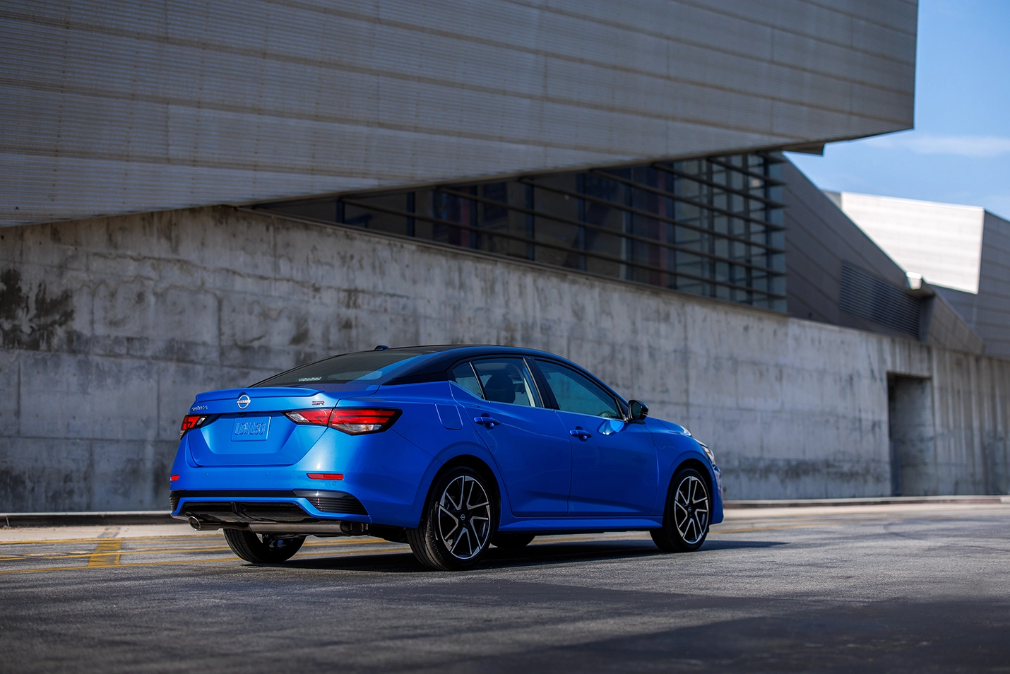 berline nissan sentra 2024 bleue arrière avec mur de béton urbain